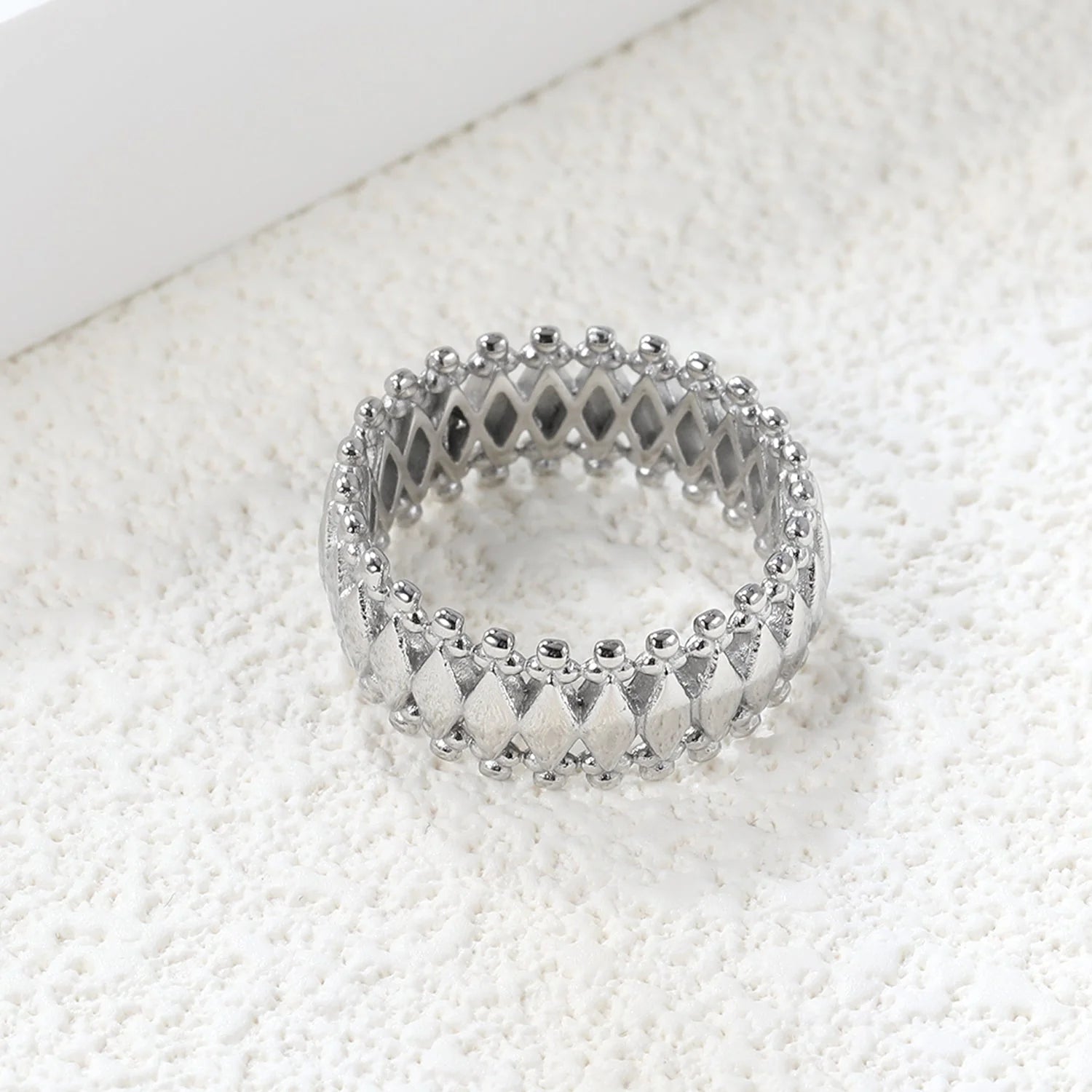 Anello composto da una pluralità di forme a diamante combinate e circondate da un anello protettivo.