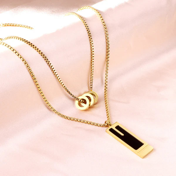 Collana a doppia catena con tre ciondoli rotondi cavi e ciondolo rettangolare con goccia d'olio nera.